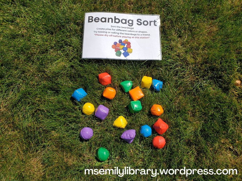 Beanbag sort station, with shiny plastic beanbags in cube, sphere, and pyramid shapes in rainbow colors.