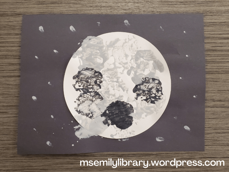 Foil Stamped Moon Craft: a large white circle is glued to a black piece of construction paper, then stamped with gray circles to simulate craters. Small gray dots surround it for stars.