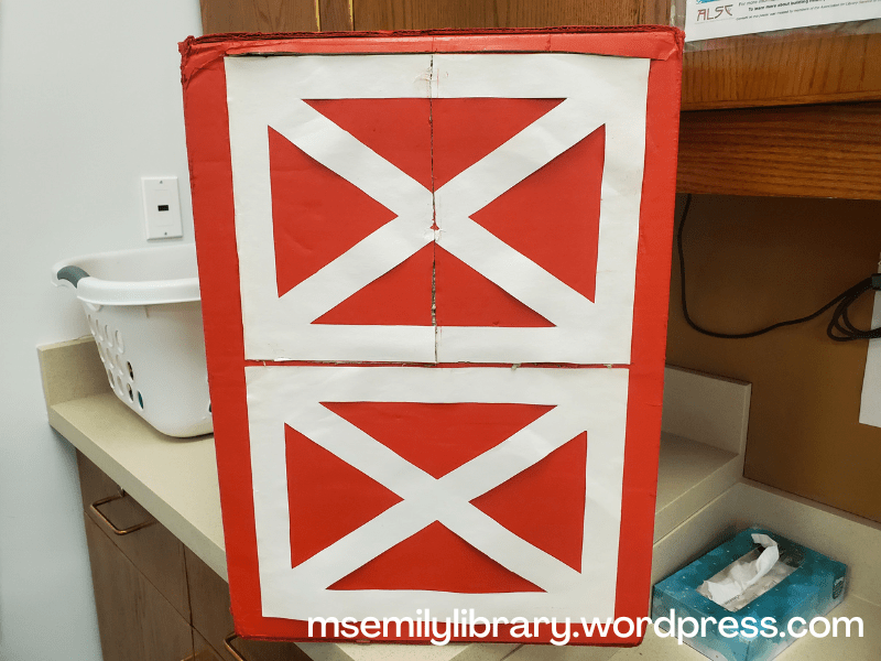 red barn box with white X details on the top and bottom "doors", with a split showing on the top door where it opens in the middle.