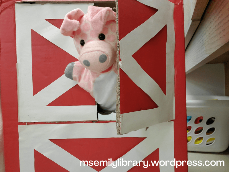 a pig puppet peeking out from the top portion of the barn box, which opens like a saloon door on the top half of the box.