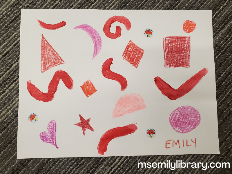 Abstract art with red shapes made by different shades of red crayons, painted squiggles, and stickers of a red umbrella.
