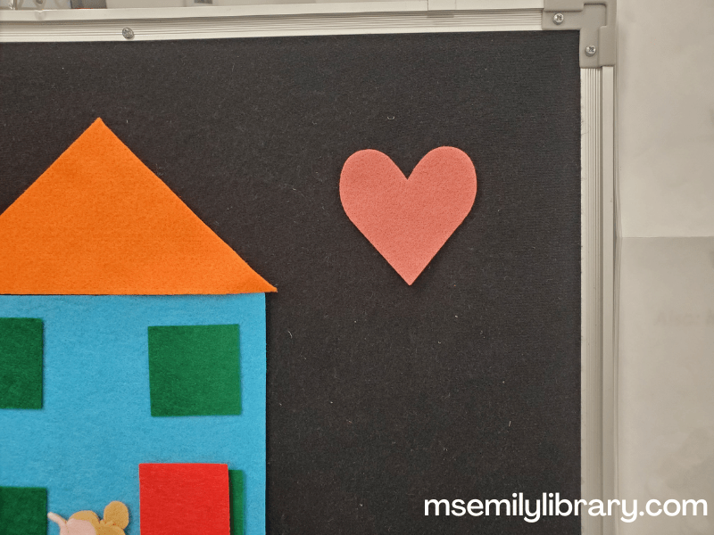 a pink felt heart shape in the corner of the flannelboard (where you can see the "build a house" felt in the background)