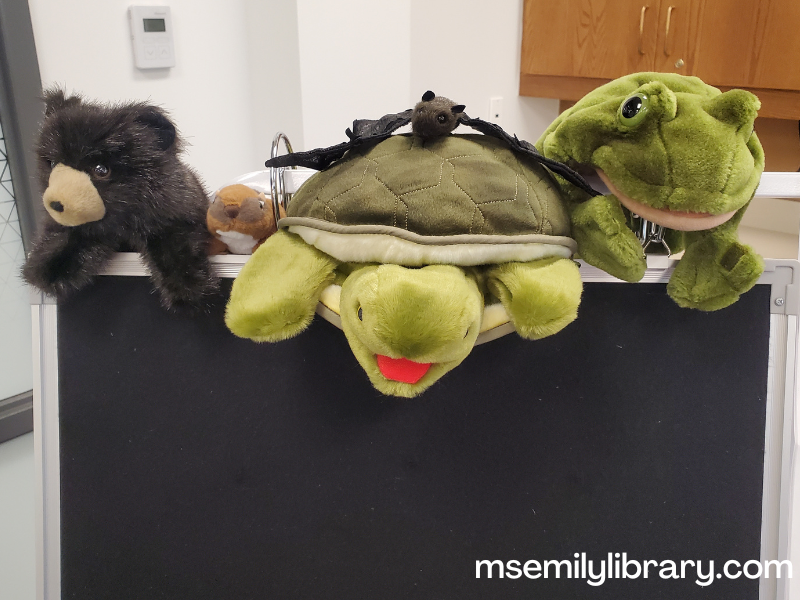 Photo of realistic animal puppets on top of a flannelboard. Includes bear, chipmunk, turtle, bat, and frog.