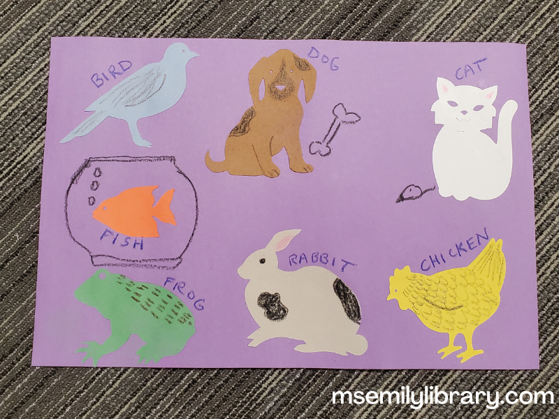Pet parade craft, showing a large purple piece of construction paper with die-cut animals - a blue bird, brown dog, white cat, orange fish, green frog, gray rabbit, and yellow chicken. They are labeled and decorated with crayon.