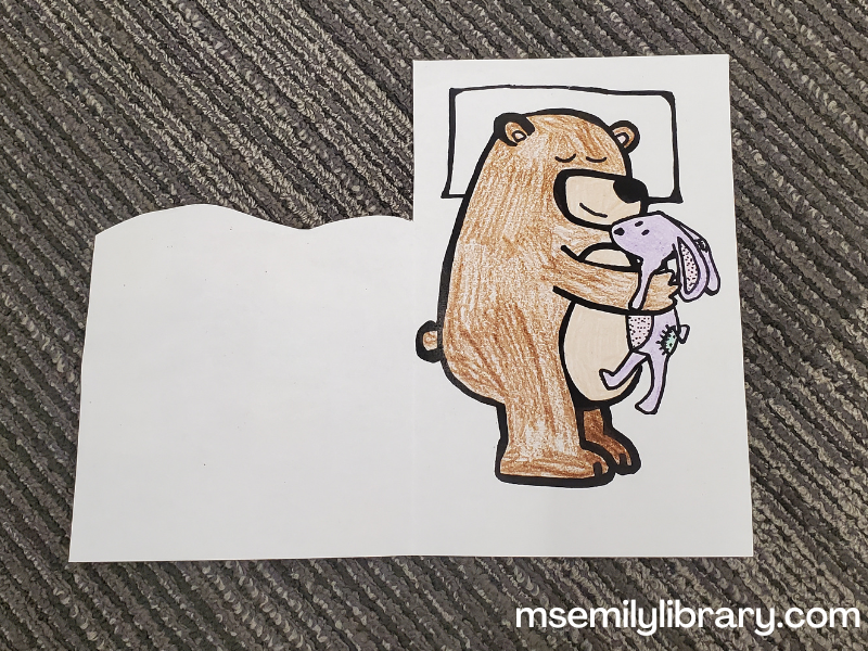 bear's blanket craft open, showing bear laying on his pillow and holding his rabbit lovey