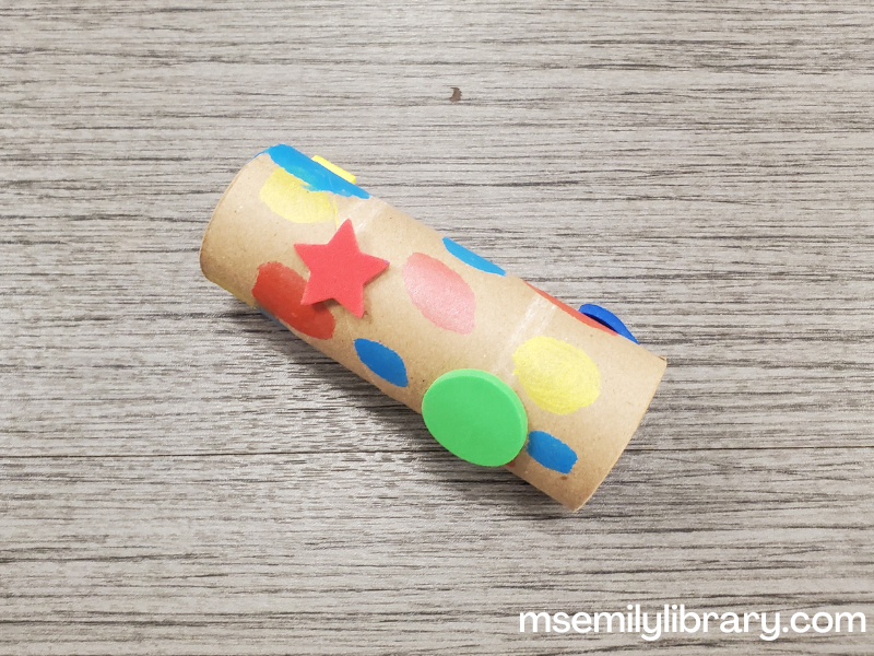 telescope craft - a brown toilet paper tube decorated with paint and foam shape stickers.