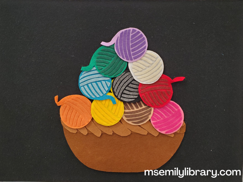 picture of ten balls of yarn flannel updated with a brown basket. The yarn colors are purple, green, white, blue, black, red, orange, yellow, brown, and pink.