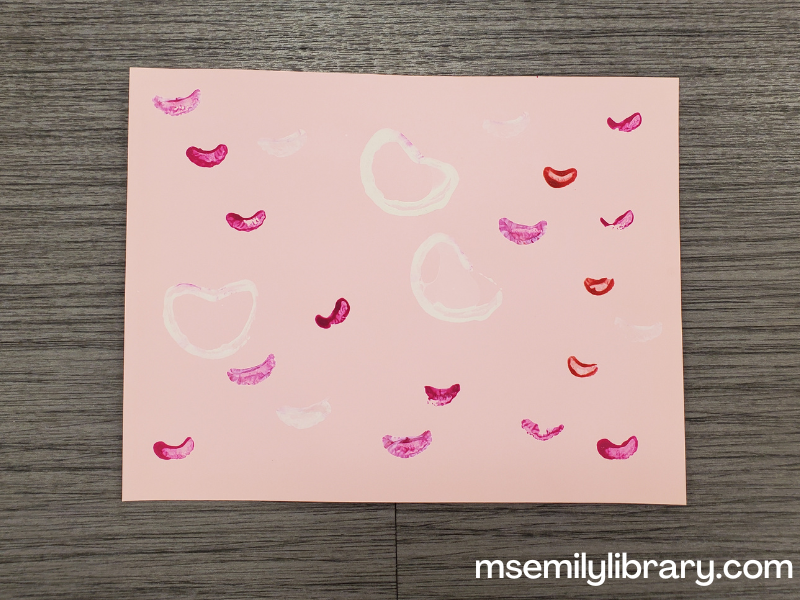 picture of light pink paper stamped with white, red, and dark pink hearts.