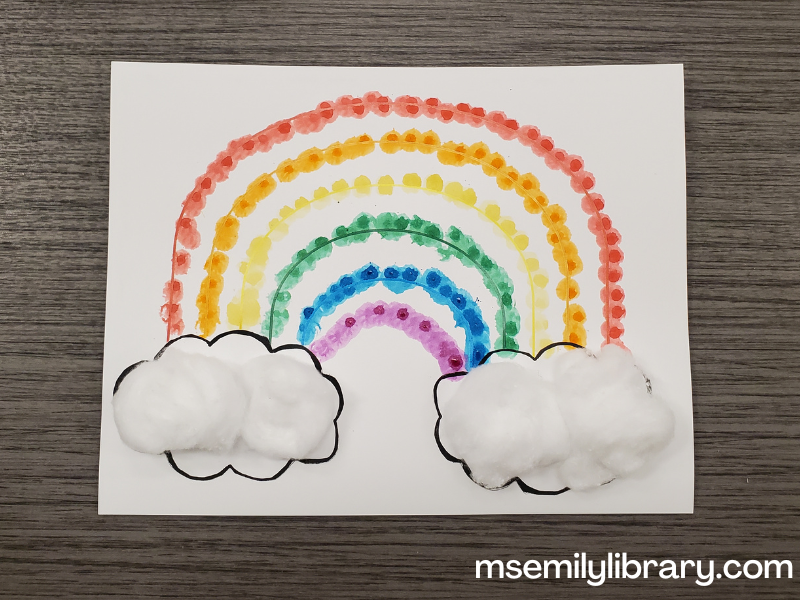 rainbow dot craft on white coverstock with dotted colored arcs and cotton balls making clouds on each end of the rainbow.