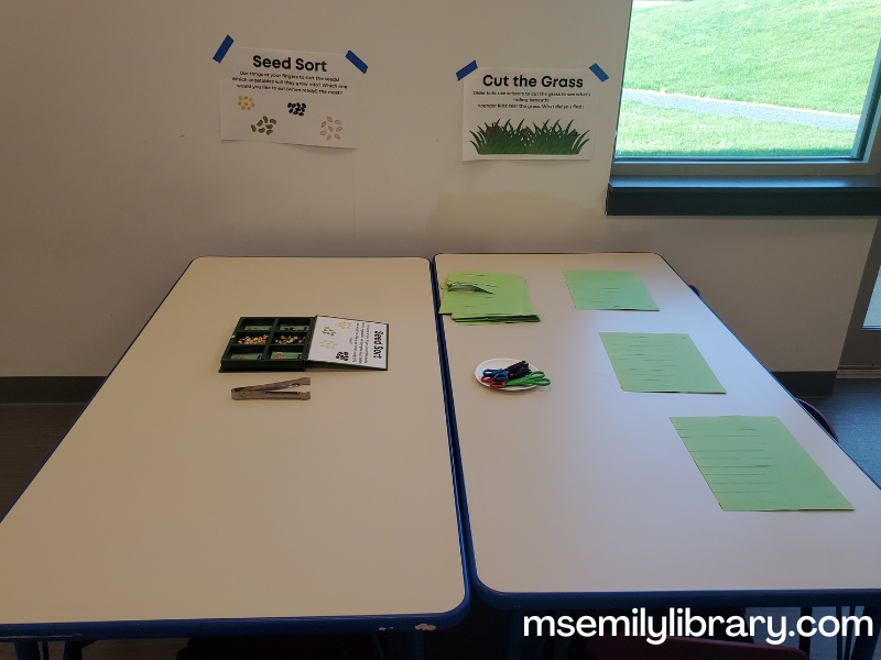 table showing a seed sorting station on one side and a cut the grass (construction paper) on the other.