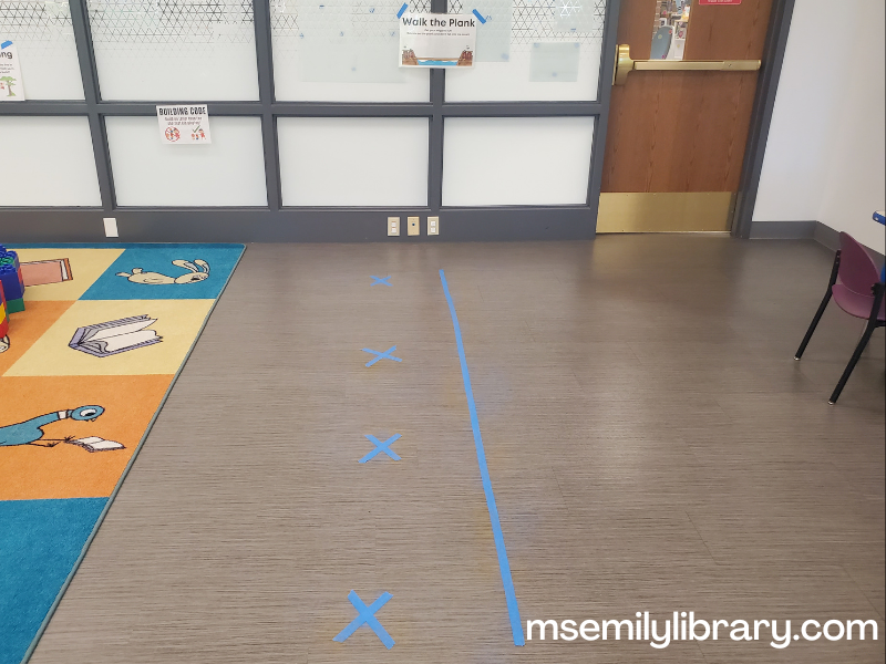 walk the plank activity, showing a blue taped line on the floor and a sign