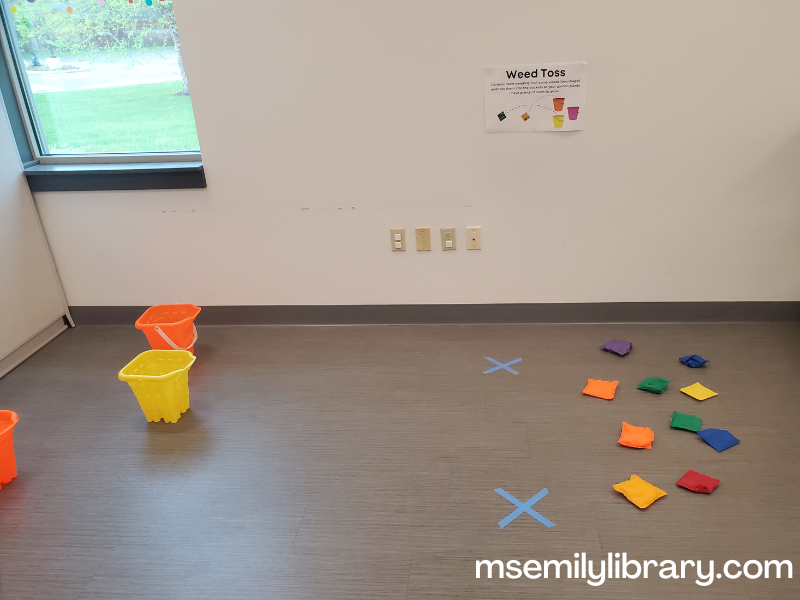 garden weed toss, showing beanbags and buckets with a sign on the wall explaining that the beanbags are weeds to pull and toss