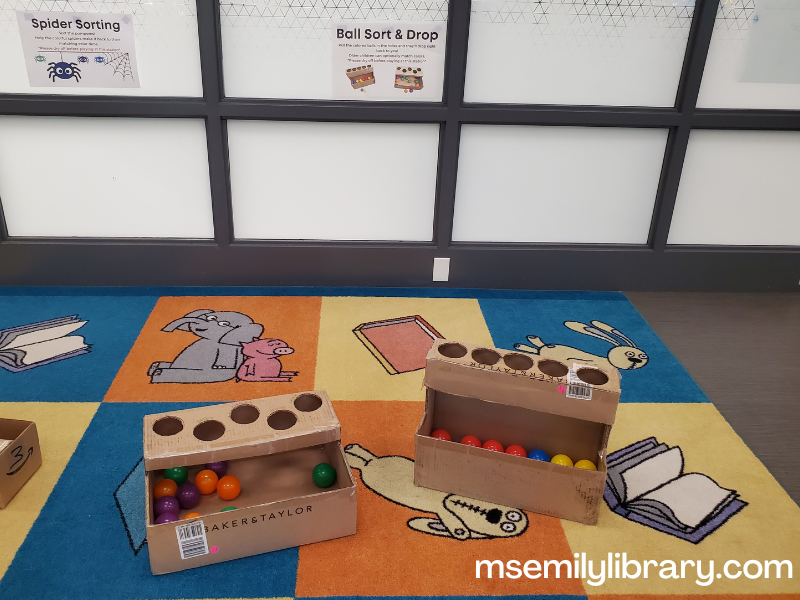 ball sort station, with brown cardboard boxes with holes in the top, cut to have a "tray" where the balls can be retrieved.