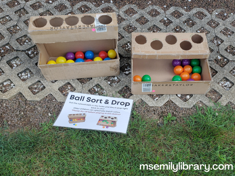 cardboard boxes cut with round holes and a tray with ball-pit balls inside