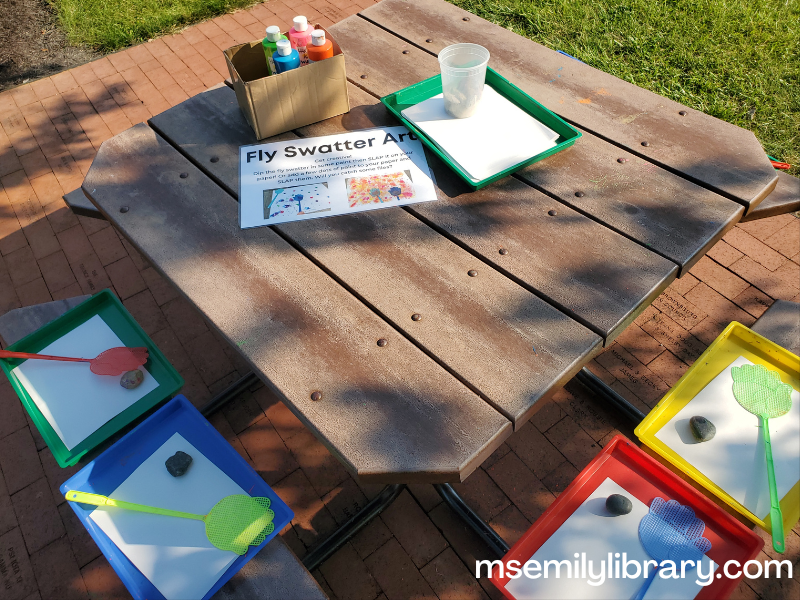 art station with hand shaped fly swatters and tempera paint on messy trays with paper