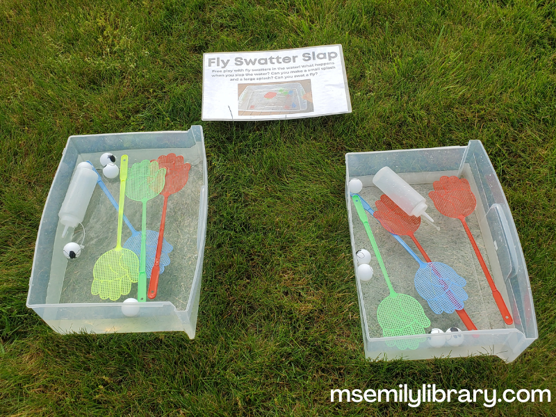 water station with hand-shaped fly swatters in a bin with ping pong balls (with flies drawn on) and squirt bottles