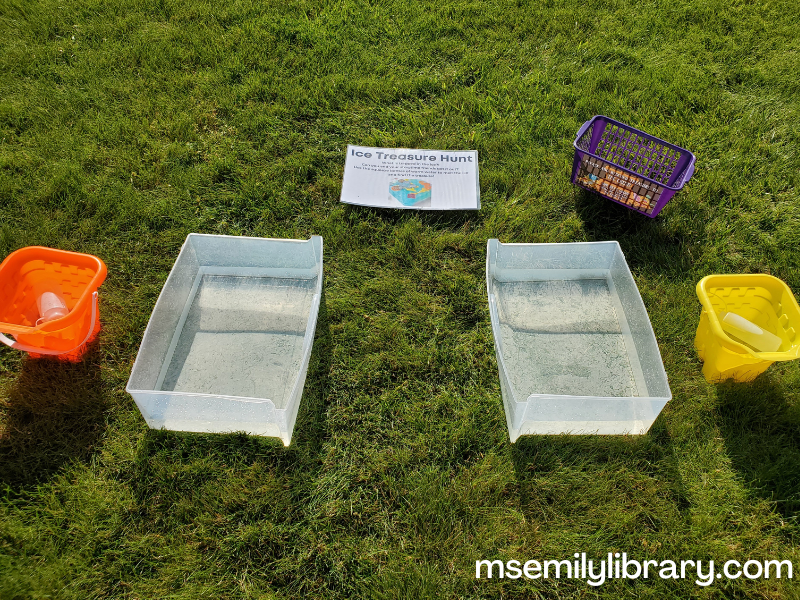 plastic bins with water, with smaller buckets beside them. a purple plastic basket is labeled as the "treasure chest" with a sign asking kids to put treasure there for the next group