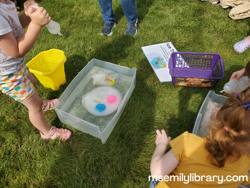 children around the bins with big ice chunks with items embedded in them