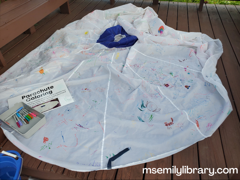 white parachute on the gazebo floor, with a small container with a few colored permanent markers