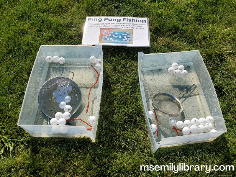 water bins with ping pong balls with letters written on, as well as plastic worms, colanders, sieves, and slotted spoons