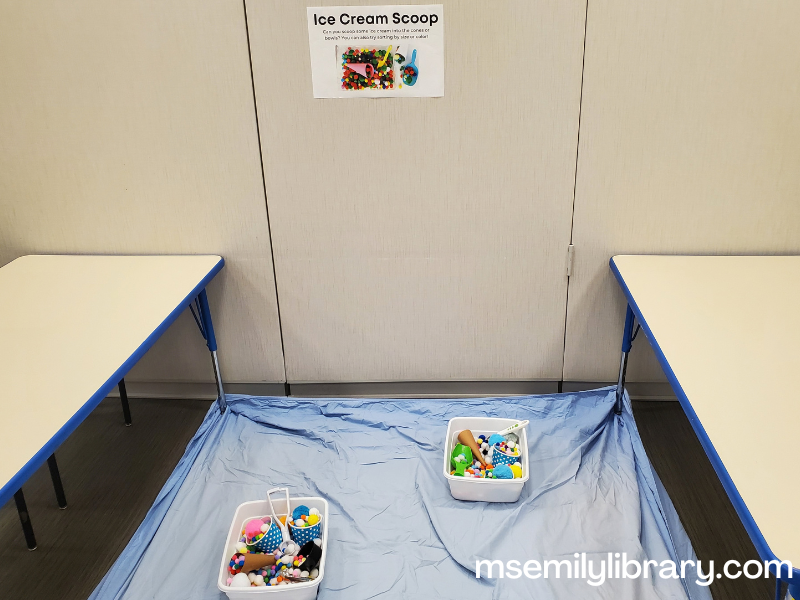 ice cream sensory bin station, showing the bins on a fitted sheet and a sign on the wall.