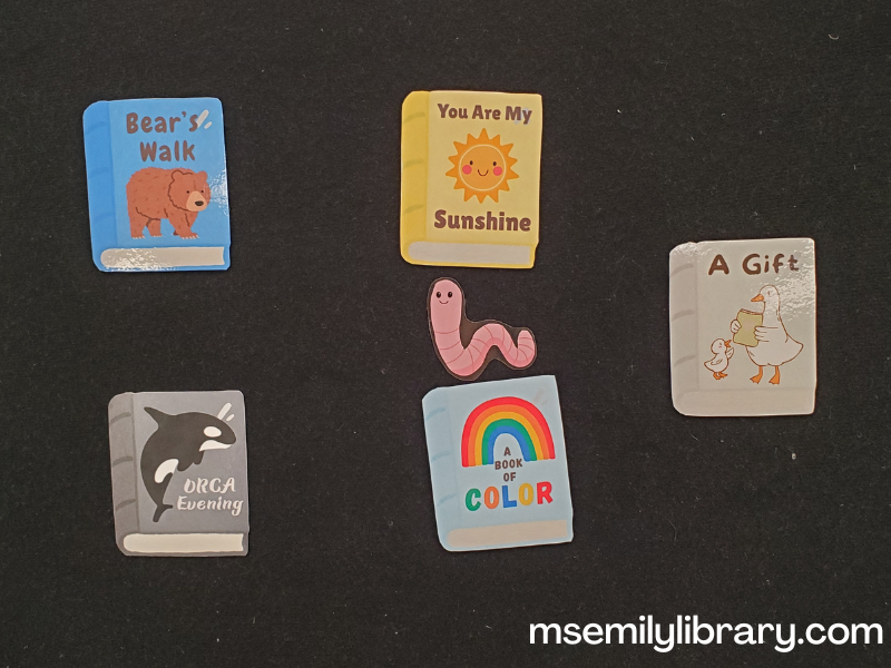 where is bookworm flannel, with five printed and laminated book covers from the library cheer flannel (bear book, sun book, orca book, rainbow book, and goose book) with a small pink earthworm among them.